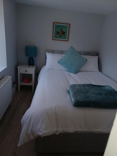 um quarto com uma cama com lençóis brancos e almofadas azuis em Kents guesthouse accommodation em Kilmacthomas