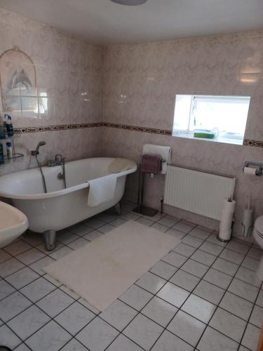 La salle de bains blanche est pourvue d'une baignoire et d'un lavabo. dans l'établissement Kents guesthouse accommodation, à Kilmacthomas