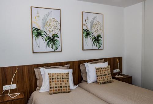 two beds in a bedroom with two pictures on the wall at Casas de Campo Curral Grande - By Cimo da Quinta in Miranda do Douro