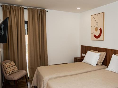 a hotel room with two beds and a chair at Casas de Campo Curral Grande - By Cimo da Quinta in Pena Branca
