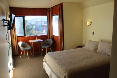 a bedroom with a bed and a table and a window at Hotel Antupiren in Puerto Montt