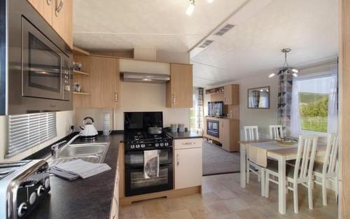 a kitchen with a stove and a table in it at HV66 - 3 Bedrooms Indoor Pool Loch Views Fishing Golf Riding Shooting Water Sports 15 Mins Drive To Beaches PASSES NOT INCLUDED Most Activities Will Not Be Available Out Of Season Please Check Before Booking in Newton Stewart