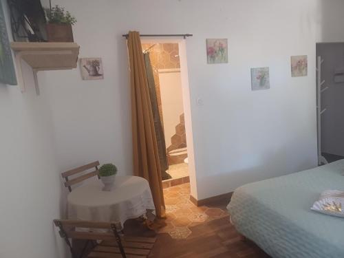 a room with a table and a bed and a mirror at Chambre d'hôte Au Jardin Le clos des vins d'Anges in Saint-Pierre-des-Champs