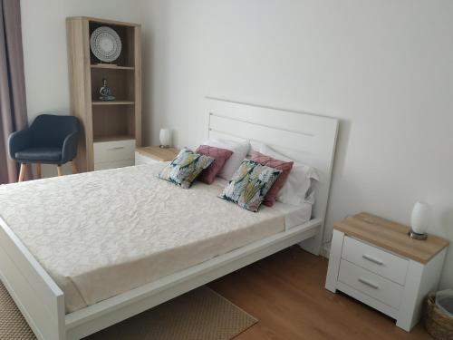 una camera da letto con letto bianco, cuscini e sedia blu di Brava a Vila Franca do Campo