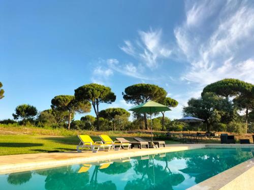a swimming pool with chairs and umbrellas at Wooden House - Monte da Cortiça in Águas de Moura