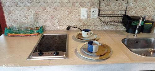 a kitchen counter with a sink and two cups and plates at Vila Bello Pontal in Coruripe