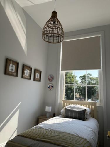 a small bedroom with a bed and a window at Field Maple -free parking -Grade II listed- first floor two bedrooms apartment in Huntingdon