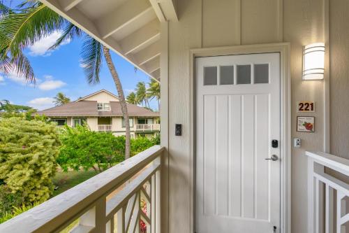 a white door on a balcony with a palm tree at Koolkondo Luxury Designer Condo in Koloa