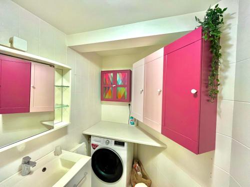 uma lavandaria com armários cor-de-rosa e uma máquina de lavar roupa em BERNARDINE - Hyper Centre Reims Famille em Reims