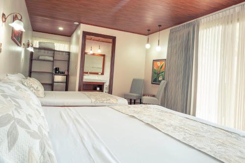 1 dormitorio con 2 camas y ventana en Miradas Arenal Hotel & Hotsprings, en Fortuna