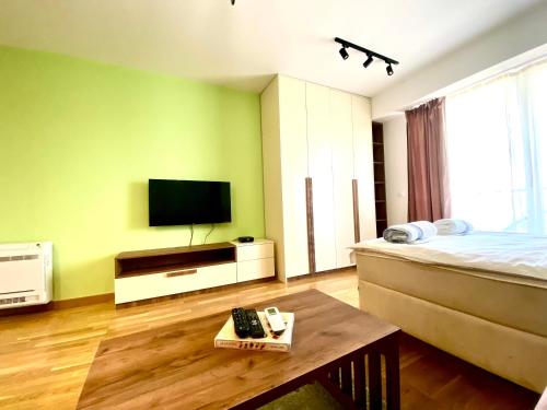 a bedroom with a bed and a tv and a table at Urban Garden APARTMENT in Skopje