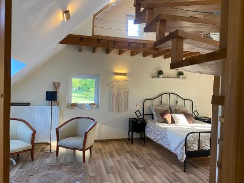 a bedroom with a bed and two chairs at Les volets bleus 