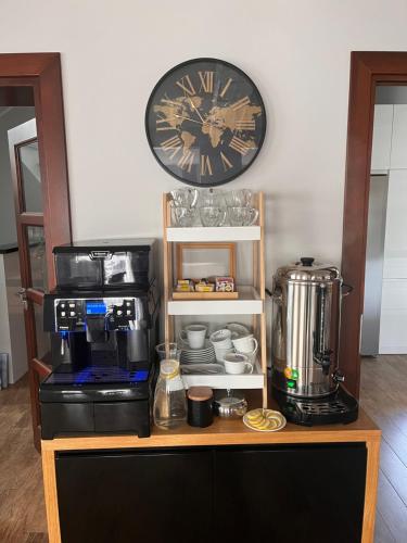 a clock on a wall above a coffee maker and a coffee machine at Willa WIKTORIA in Krynica Zdrój