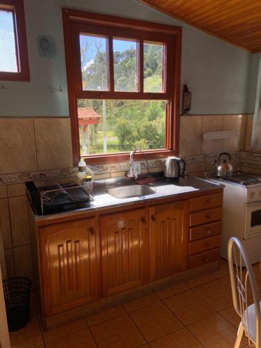 a kitchen with a sink and a window at Aconchegante Casa Serrana ao lado da Igreja Matriz in Urubici