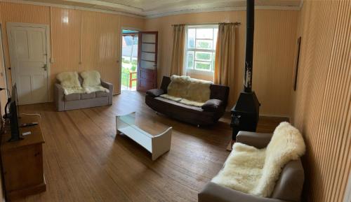 a living room with two couches and a stove at Aconchegante Casa Serrana ao lado da Igreja Matriz in Urubici