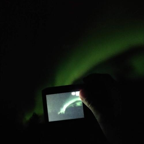 a person taking a picture with a cell phone in the dark at Toola-Lodge in Syöte