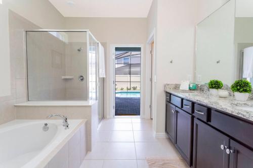 a white bathroom with a tub and a sink at 7-bed w Pool, Game Room and Free Resort Access in Davenport
