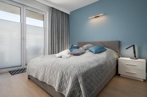 加茨比亞格拉的住宿－Morskie Apartamenty Albatros i Góral，一间卧室配有一张蓝色墙壁的床和一扇窗户
