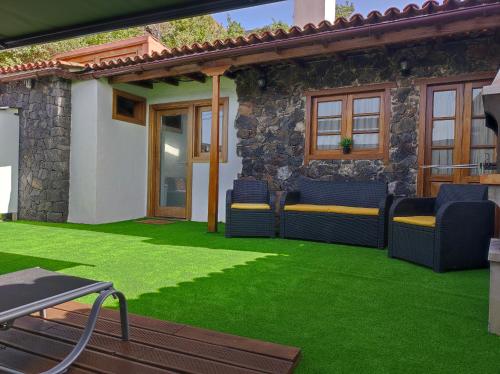 a patio with green grass and blue chairs at House to relax El Tanque in Tanque