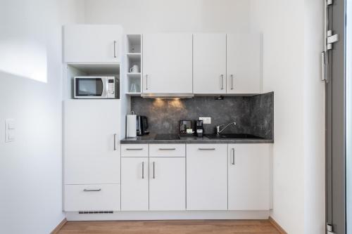 a white kitchen with white cabinets and a sink at FeelGood Apartments LakeLiving inklusive Garagenplatz in Vienna
