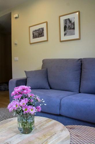 a living room with a blue couch and a table with flowers at Apartaments Areny - L'Amfitriona in Esterri d'Àneu