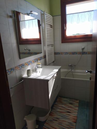 L'appartamento Italia B. في تريفيزو: حمام مع حوض ومرآة وحوض استحمام
