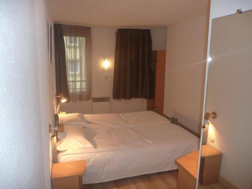 a bedroom with a white bed and a window at Hotel Primo Colmar Centre in Colmar