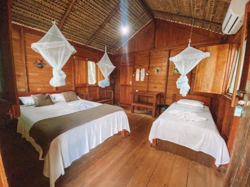 two beds in a room with wooden walls at Dolphin Lodge in Careiro