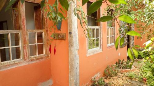 un edificio naranja con dos ventanas y un árbol en Chalé das Flores, en Tiradentes