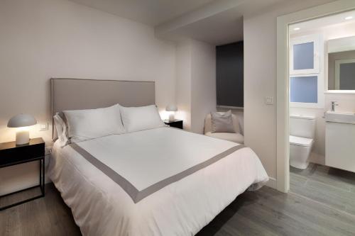 um quarto com uma grande cama branca e uma casa de banho em INMálaga Plaza De Las Flores em Málaga