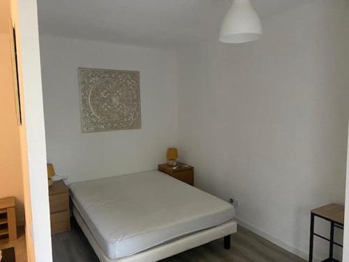 Habitación blanca con cama y una foto en la pared en Superbe appartement dans résidence avec piscine en Toulouse