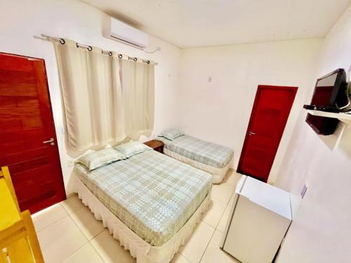 a bedroom with two beds and a red door at Pousada e Chalés Recantos do Mar in Barra Grande