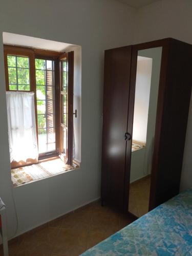 a bedroom with a mirror and a bed and a window at ΠΗΛΙΟ- ΤΟ ΕΞΟΧΙΚΟ ΤΗΣ ΑΝΝΑΣ- ΑΦΗΣΣΟΣ in Afissos