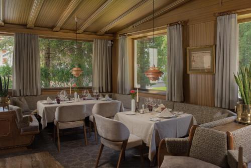 a dining room with tables and chairs and windows at Hotel Genziana in Selva di Val Gardena