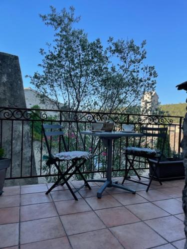 a patio with a table and chairs on a balcony at Charmante chambre dans belle Maison typique du Village in Lagorce