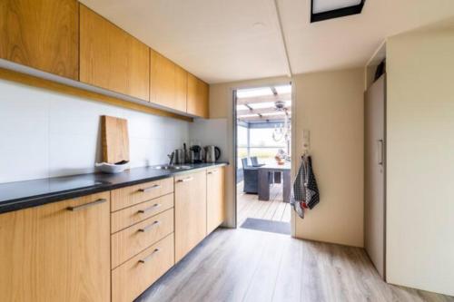 a kitchen with wooden cabinets and a counter top at Buiten Huisje aan de Vaart 1 in Matsloot