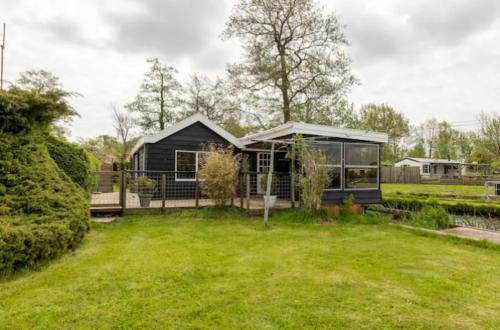 a small black house in a field with a yard at Buiten Huisje aan de Vaart 1 in Matsloot