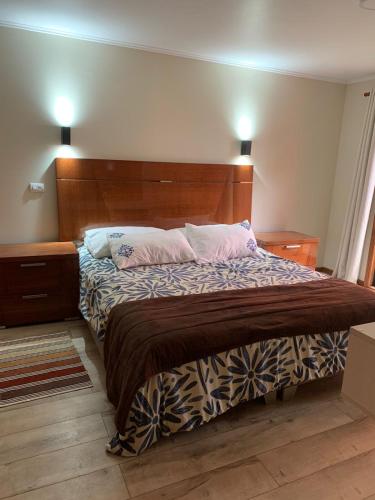 a bedroom with a large bed with two pink pillows at Hotel Boutique Family Suites in Panguipulli