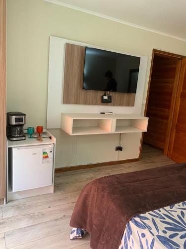 a hotel room with a television and a bed at Hotel Boutique Family Suites in Panguipulli