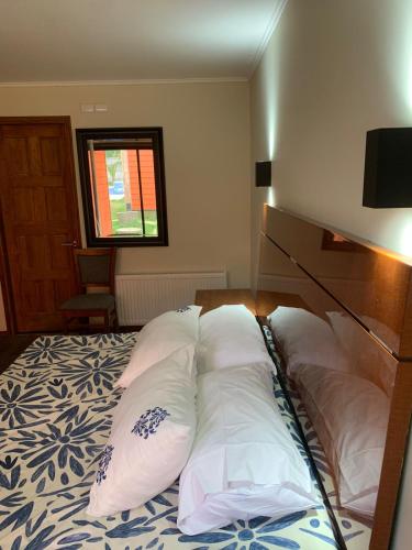 a bedroom with a bed with four pillows on it at Hotel Boutique Family Suites in Panguipulli