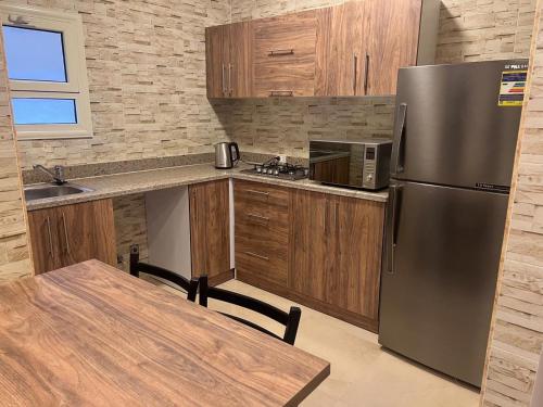La cuisine est équipée d'un réfrigérateur en acier inoxydable et de placards en bois. dans l'établissement MARINA SKY, à Hurghada