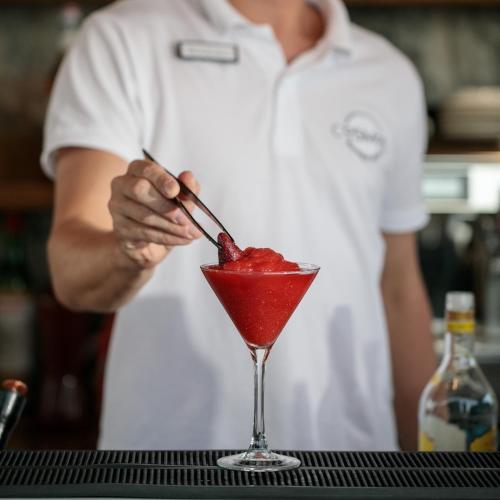 a person stirring a red drink in a martini glass at Cosmos Hotel in Plaka