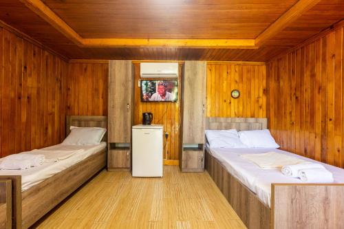 two beds in a room with wooden walls at Eco Cottage in Kutaisi