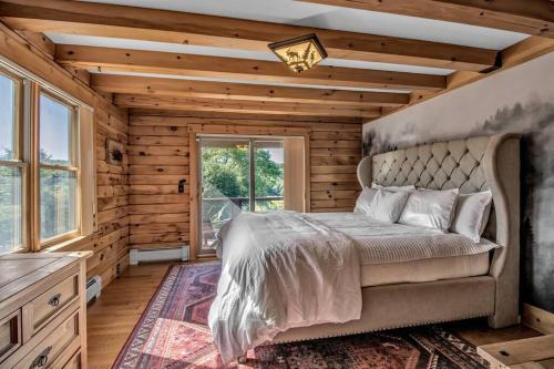 ein Schlafzimmer mit einem Bett in einem Zimmer mit Holzwänden in der Unterkunft Ischua Ridge Ellicottville Private Resort. Ski, Explore, Rest! in West Valley