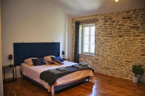 a bedroom with a bed and a brick wall at Le Clos Ayanna in Crémieu