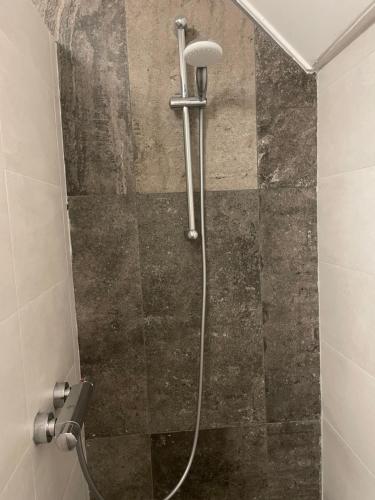 a shower with a hose in a bathroom at Schrijvershuisje - sfeer & stilte Zeeuws Vlaanderen in Zaamslag