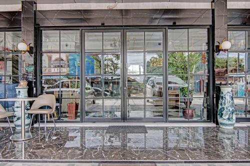 une façade de magasin avec des fenêtres en verre, des tables et des chaises dans l'établissement Super OYO Collection O 91397 Tasqya Costel Syariah, à Pekanbaru