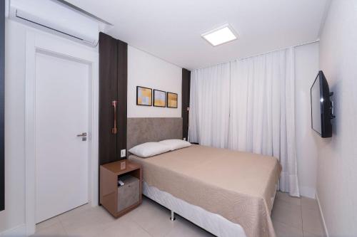 a small bedroom with a bed and a television at Adra 205 - Apartamento no centro de Bombinhas - Rooftop com piscina e academia - À poucos metros da praia - (Consultar serviços de roupas de cama e banho) in Bombinhas