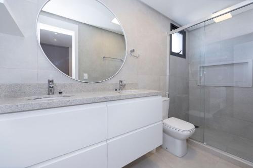 a bathroom with a sink and a mirror and a toilet at Adra 205 - Apartamento no centro de Bombinhas - Rooftop com piscina e academia - À poucos metros da praia - (Consultar serviços de roupas de cama e banho) in Bombinhas