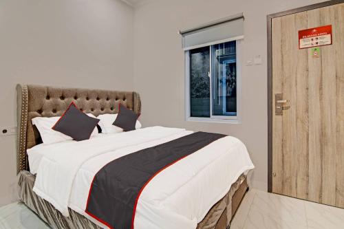 a bedroom with a large bed and a window at Super OYO Collection O 91397 Tasqya Costel Syariah in Pekanbaru